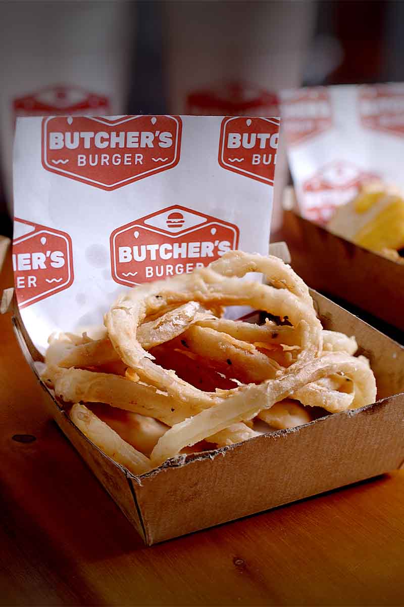 Golden onion rings on Butcher’s Burger branded paper